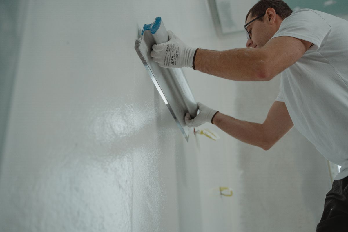 Plasterer skimming a smooth interior wall with a wide finishing blade